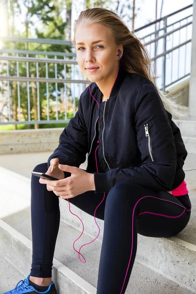 Młoda kobieta w sprawny słuchanie muzyki na Smartphone — Zdjęcie stockowe