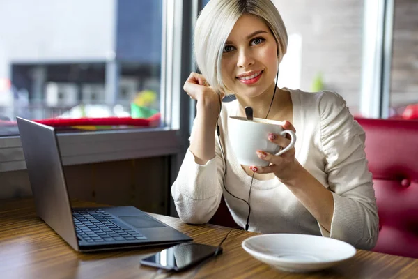 Hermosa mujer joven con taza de café y portátil en el café — Foto de Stock