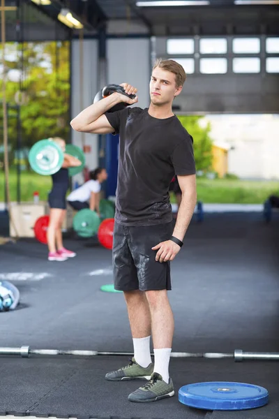 Selbstbewusster Athlet mit Kettlebell im Fitnessstudio — Stockfoto