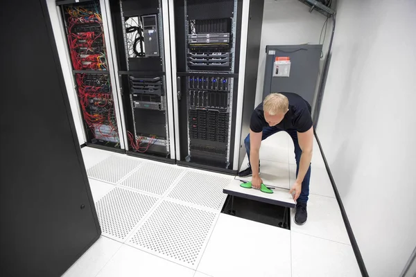 Engenheiro de TI levantando telha do assoalho usando ventosas em Datacenter — Fotografia de Stock