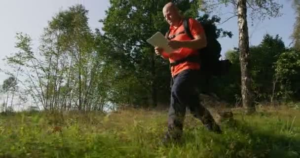 Active man hiker navigate using map and compass in beautiful forest at sunset