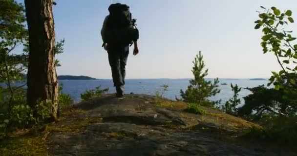 Hombre sano con gran mochila camina por la montaña junto al mar al atardecer — Vídeos de Stock