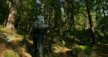 Etkin adam dik dağ yolunda günbatımında hiking büyük sırt çantası ile