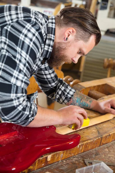 Hantverkaren slipning en gitarr halsen i trä på verkstad — Stockfoto