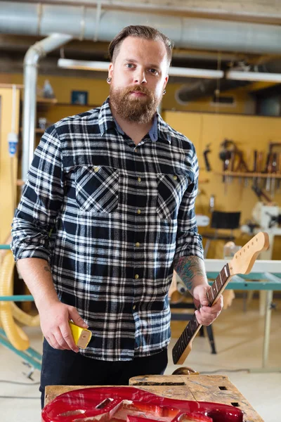 Werk op de hals van een houten gitaar in werkplaats timmerman — Stockfoto