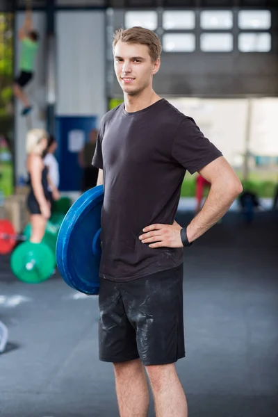 Confident Athlete Carrying Weight Plate In Warehouse — Stock Photo, Image