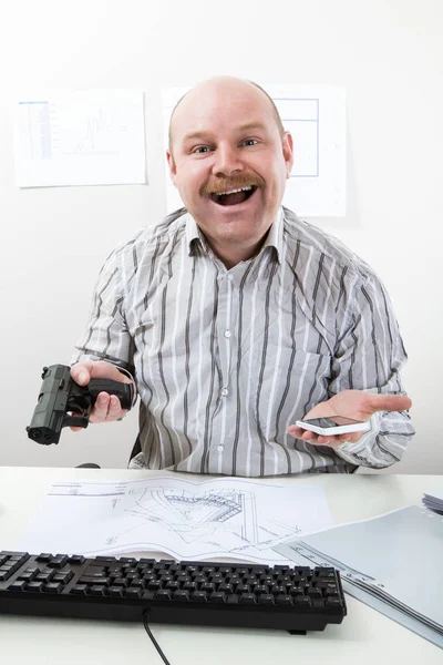 Funny Man Holding Handgun And Mobile Phone At Desk — Stock Photo, Image