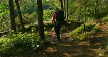 Büyük sırt çantası ile sportif insan dik dağ yolu günbatımında yürüyor.