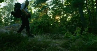 Gün batımında güzel orman yolunda yürürken sırt çantası ile etkin adam