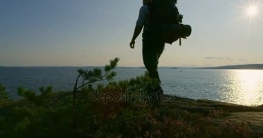 Dağ deniz, gün batımında kampa sırt çantası ile etkin adam