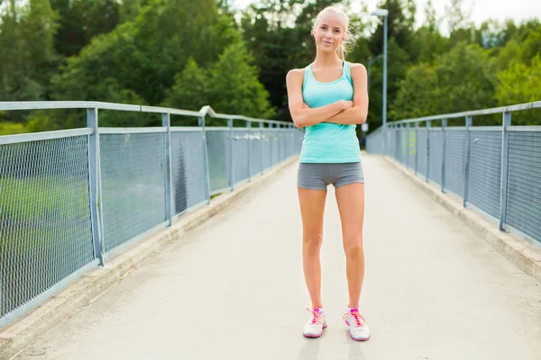 Selbstbewusste und lächelnde junge Läuferin macht Pause nach dem Training — Stockfoto