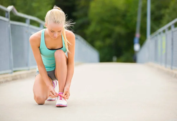 Fiatal nő runner odakötő cipőfűzők-híd — Stock Fotó