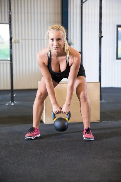 Deportista femenina determinada haciendo ejercicio con Kettlebell en Warehous —  Fotos de Stock