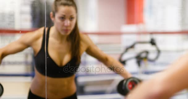 Mujer sana y bien entrenada levanta pesas en el espejo en el gimnasio — Vídeos de Stock