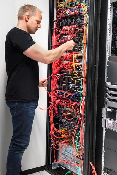 Ingenieur überprüft mit Netzwerkkabeln, die mit Servern verbunden sind — Stockfoto