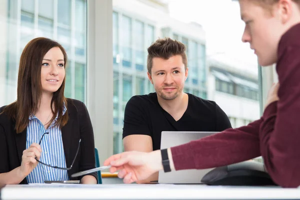 Business People Looking At Colleague Explaining At Desk — Stock Photo, Image