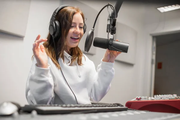 Anfitrión femenino comunicándose en el micrófono en el estudio de radio — Foto de Stock