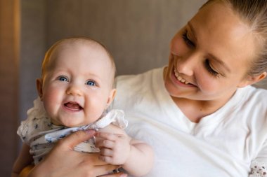 Mutlu ve bakım annesi ile gülümseyen şirin bebek kız