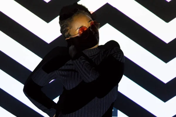 Modèle de lumière créative sur la pose femme cool avec des lunettes de soleil — Photo