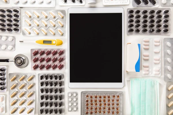 Цифровой планшет, окруженный красочными таблетками на столе — стоковое фото