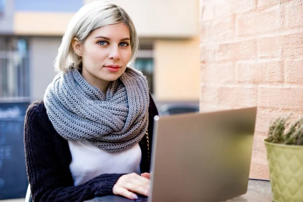 Ung kvinna som arbetar på laptop på uteservering — Stockfoto