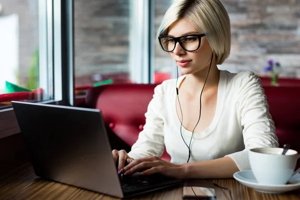 Bloggerin trägt Brille, während sie Laptop im Café benutzt — Stockfoto