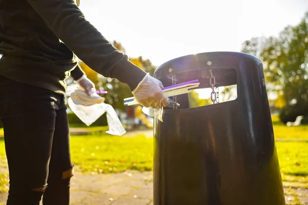 Voluntario poniendo pajitas en cubo de basura en el parque —  Fotos de Stock