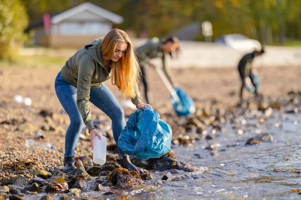 Jóvenes voluntarios limpiando la playa en un día soleado — Foto de Stock