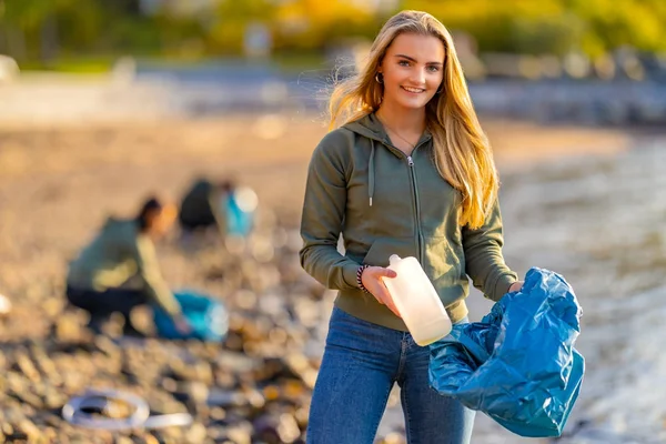Voluntario sosteniendo botella y bolsa de basura en la playa — Foto de Stock