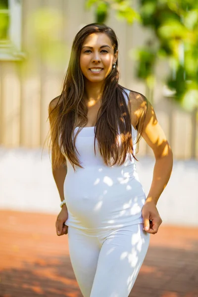 Красивая, улыбающаяся беременная женщина, стоящая дома в саду — стоковое фото