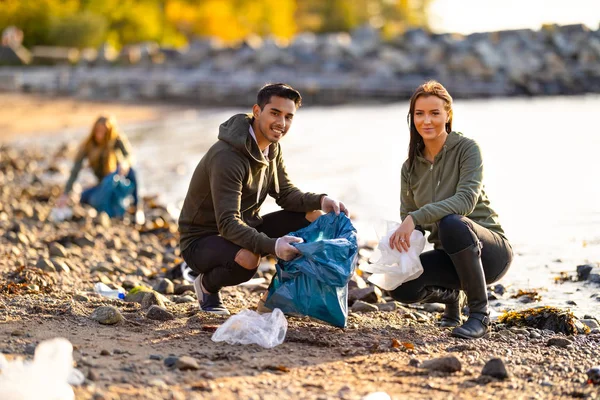Retrato de voluntarios de protección ambiental sonrientes limpiando la playa — Foto de Stock