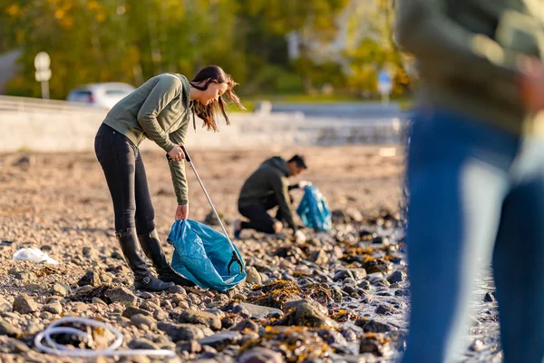 Voluntarios dedicados a limpiar la playa en un día soleado Imagen de archivo