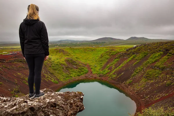 Блондинка - дослідниця, що стоїть на скелі і дивиться на озеро Кратер Керид. — стокове фото