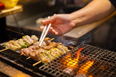 Satıcı Japonya 'da barbekü ızgarasında et hazırlıyor.