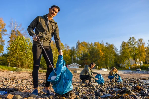 Güneşli bir günde gönüllülerle plajı temizleyen adam. — Stok fotoğraf