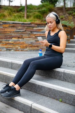 Sportif Genç Kadın Kulaklıklı ve Akıllı Telefonlu Müzik Dinliyor