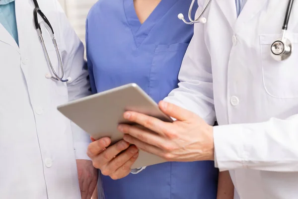Læge i medicinsk team diskuterer patient rapport på tablet computer på hospitalet - Stock-foto
