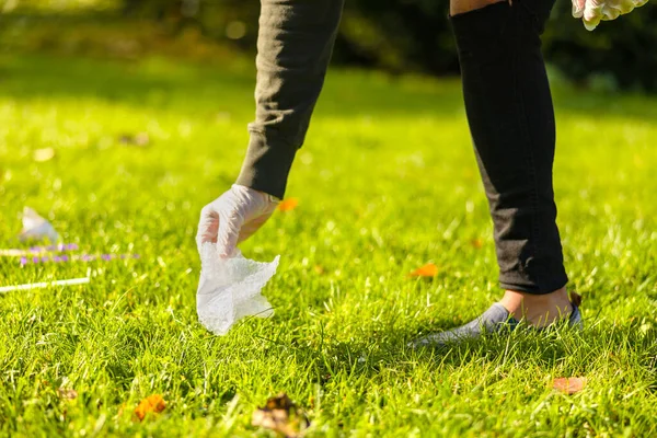 Erkek gönüllü çimlerden plastik topluyor.
