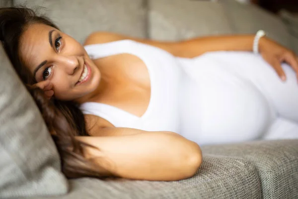 Счастливая беременная женщина лежит на диване с животом — стоковое фото