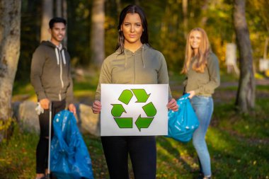 Confident volunteer woman holding recycling symbol placard clipart