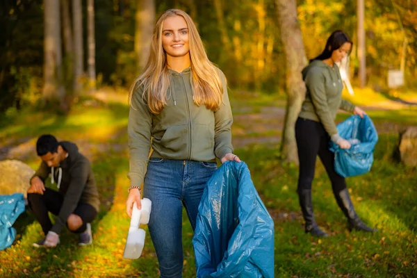 Joven voluntaria sosteniendo bolsa de basura en el parque —  Fotos de Stock