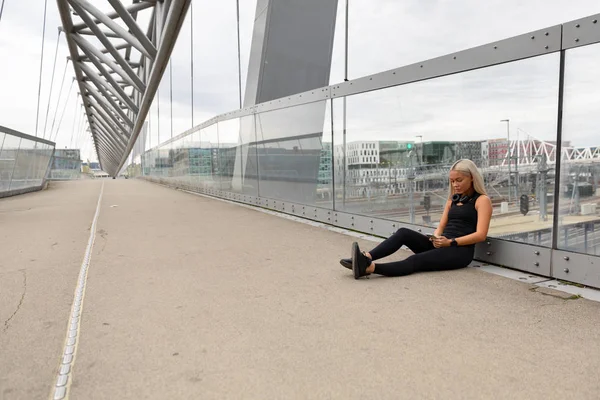 Biegacz odpoczywający na mostku po treningu i sprawdzający wydajność Wokout — Zdjęcie stockowe