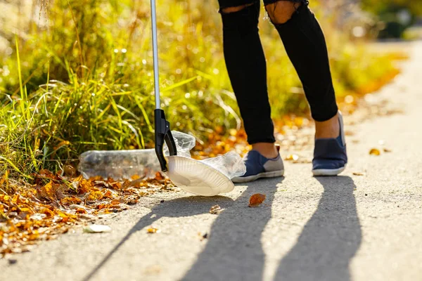 Erkek gönüllü çimlerden plastik topluyor. — Stok fotoğraf