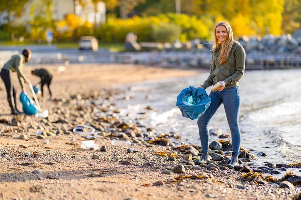 Jóvenes voluntarios dedicados a limpiar la playa en un día soleado Imágenes de stock libres de derechos