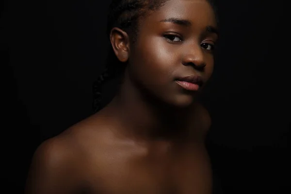 Zelfverzekerde en mooie Afrikaanse vrouw met donkere huid op zwarte bakgrond — Stockfoto