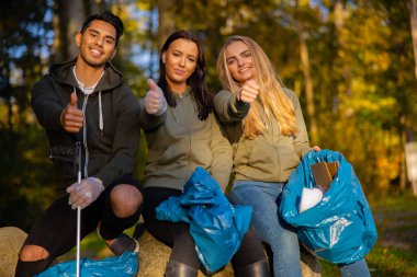 Smiling volunteers showing thumbs up at park