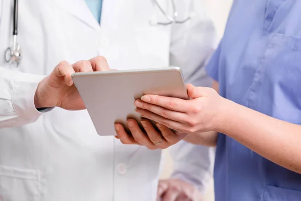 Doctor and nurse discussing patients tests at tablet computer in hospital — Stock Photo, Image