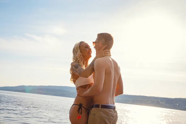 Joyeux couple riant amoureux riant de la plage contre le soleil — Photo