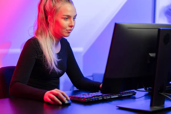 Enfocado rubia gamer chica jugando en línea video juego en su computadora personal . — Foto de Stock