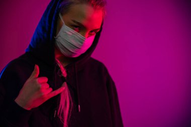 Yorgun ve depresif bir kadın koruyucu yüz maskesi takmış, çok renkli ışıkları var.